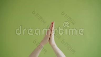 特写拍手镜头，在绿色背景下显示拇指向上的手势